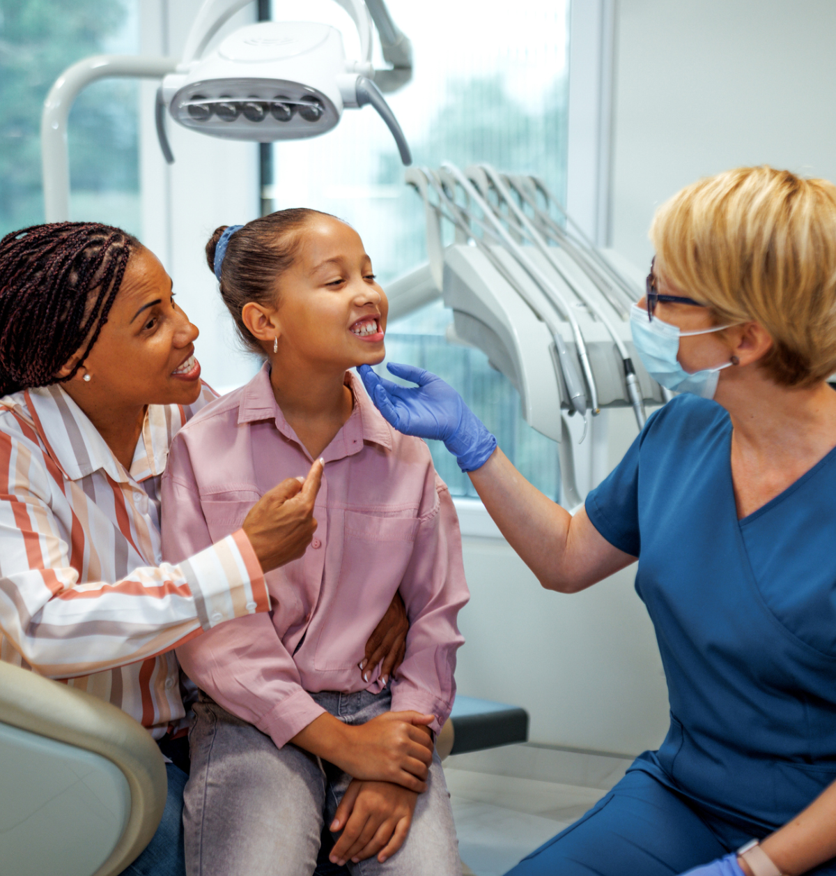 Dentist examining child's teeth with parent