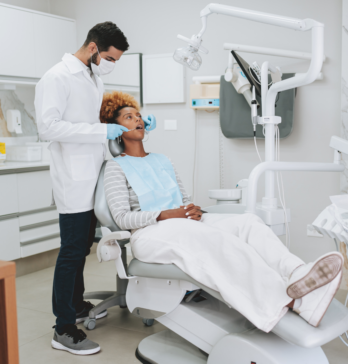Dentist examining patient in clinic chair